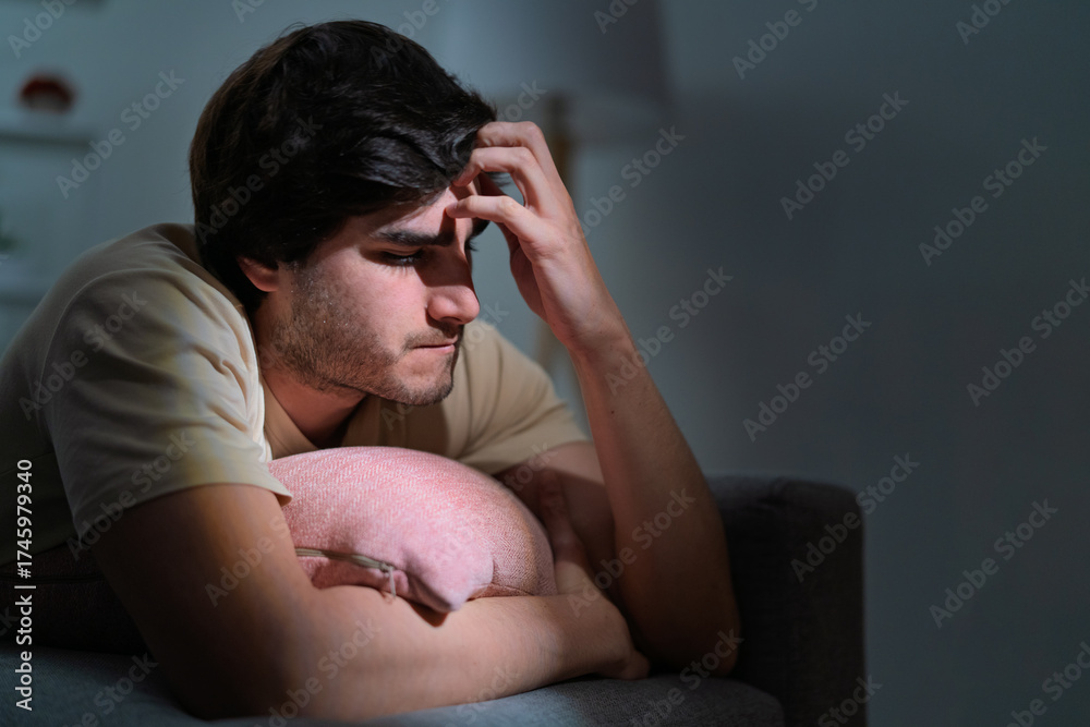 Obraz premium Young man suffering depression, stress, headache at night