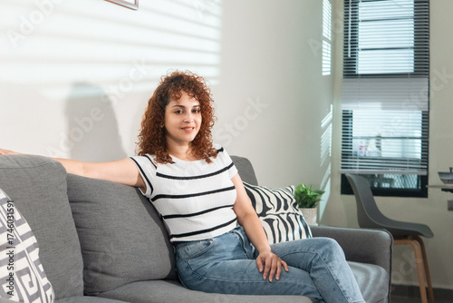 Free Download Hispanic woman relaxing on sofa in modern apartment - GFXLoad