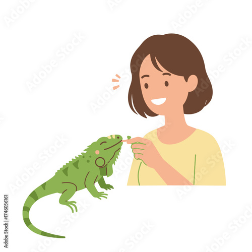 A woman happily feeding a green iguana with a smile.