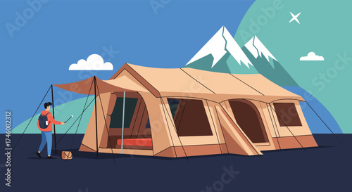 A large family camping tent with a person setting it up near mountains.