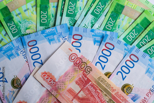 different denominations Russian banknotes are spread out on flat surface. image showcases colorful 200, 2000 and 5000 ruble notes, highlighting their unique designs. close up.