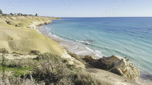Sunny winter day at Port Willunga Beach, white cliffs and waves crashing on shore, jetty pylons rising from water, St Vincent Gulf, Great Australian Bight, Fleurieu Peninsula, South Australia