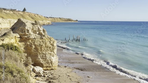 Sunny winter day at Port Willunga Beach, white cliffs and waves crashing on shore, jetty pylons rising from water, St Vincent Gulf, Great Australian Bight, Fleurieu Peninsula, South Australia