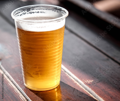 Plastic cup of ice cold beer at beer festivals like Oktoberfest celebrated in October 2025 with blurred background