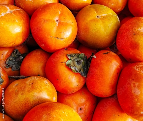 selective image of fresh ripe persimmon fruit (Diospyros kaki) displayed together at a local market for sale. ideal for fruit background and vegetarian diet or natural food design theme