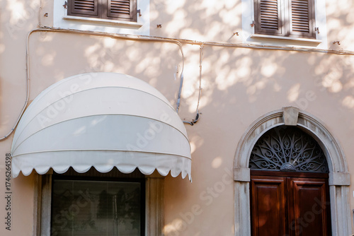 Close-up of a White Scalloped Canvas Awning and Blind Signboard Over a Shop Window on a Pale Pink Historical Building Facade in Italian Sunlight. Mock up