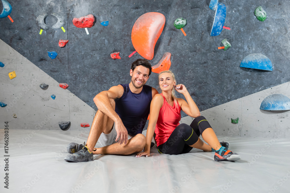 Fototapeta premium Happy Positive Joyful Couple Sitting Embracing Prior To Bouldering Climbing up the Wall Together in Sport Hall.