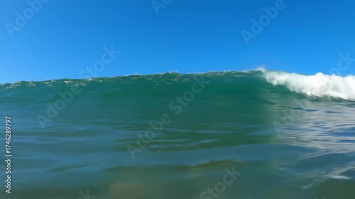 Powerful Blue Ocean Wave Crashing Under a Clear Sky.