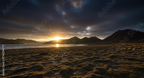 Dramatic sunset over a tranquil lake, with dark mountains silhouetted against the vibrant sky.