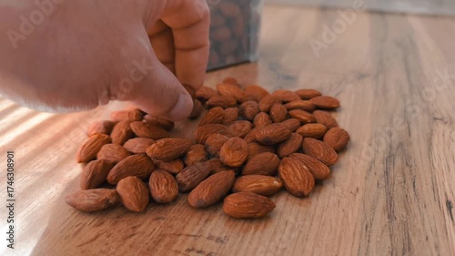 A close-up video shot of sliced almonds slowly pouring onto a wooden table, creating a natural and appetizing pile. 