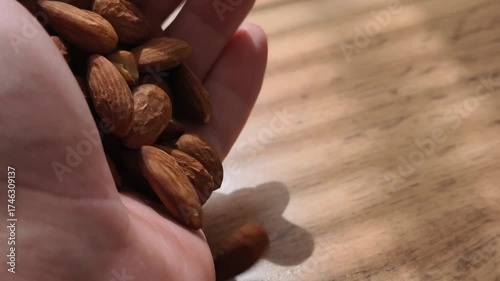 A close-up video shot of sliced almonds slowly pouring onto a wooden table, creating a natural and appetizing pile. 