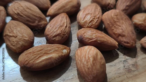 A close-up video shot of sliced almonds slowly pouring onto a wooden table, creating a natural and appetizing pile. 