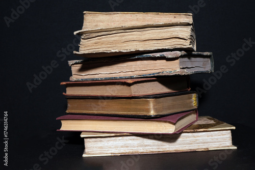 Stack of old books with gilded edges, cracked spines and aged paper illuminated by soft studio light, evoking a classic atmosphere of libraries, learning and antique charm.
