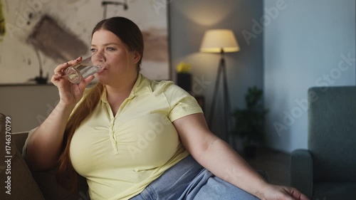 Happy young woman taking pill with water at home, dietary supplements, vitamins