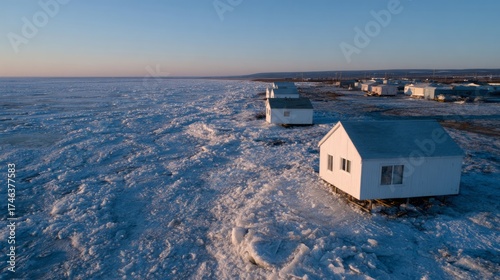 Coastal winter horizon frames isolated ice-bound cabins, evoking serenity, and echoes of Narnia, celebrating Iceberg Day and Polar Bear Plunge