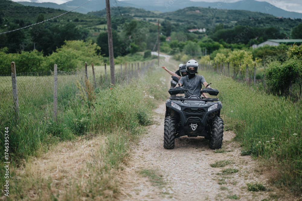 Fototapeta premium Friends enjoying an outdoor adventure on an all-terrain vehicle in the countryside. The serene surroundings and open fields provide a picturesque backdrop for the thrilling experience.