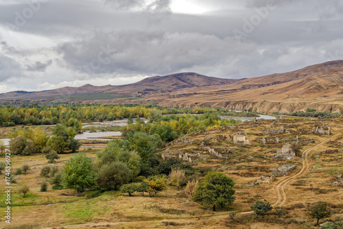 A desolate landscape near the Uplistsikhe Cape Town in Georgia with a river running through it. The sky is cloudy and the sun is not visible in autumn.