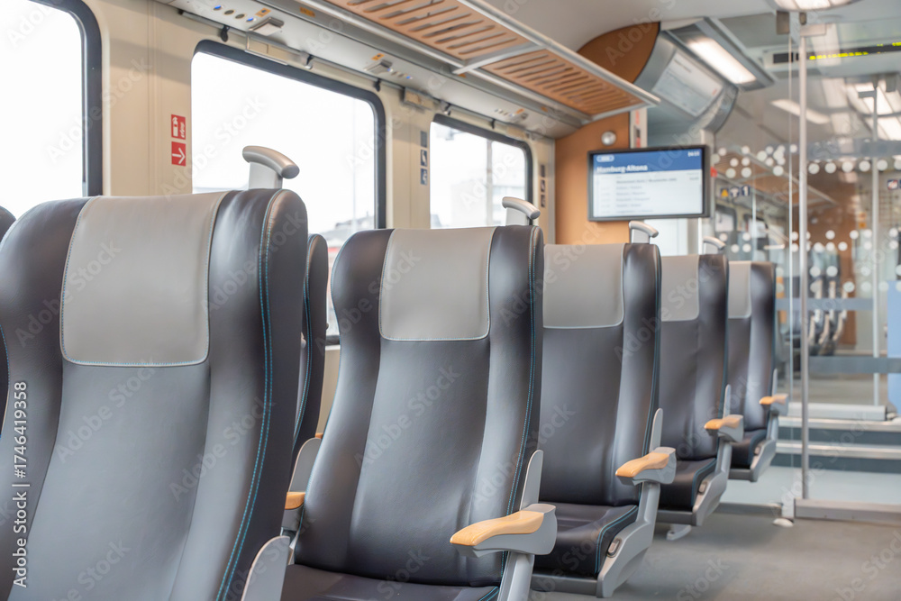 Obraz premium Train seats row. Modern leather train seats are arranged in a row with large windows on the side. Bright light floods the clean and comfortable interior.