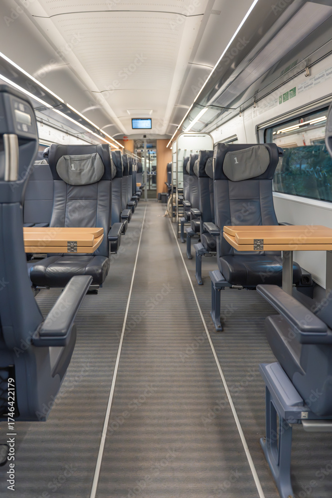 Obraz premium First-class seats with foldable wooden tables line both sides of the aisle. Modern, clean, and ready for travel.
