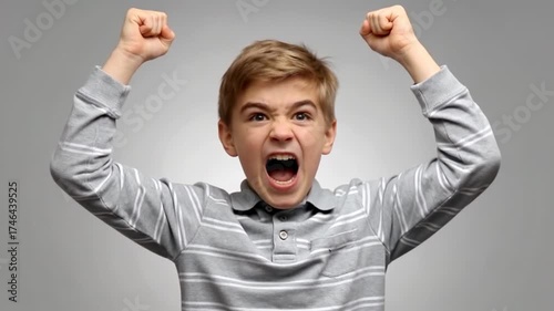 Young boy shouting with fists raised in anger or excitement
