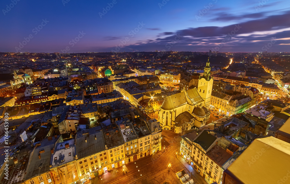 Naklejka premium Majestic aerial view of Lviv's historic Old Town and Latin Cathedral at night.