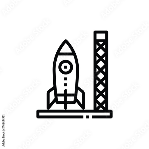 A black rocket on a launchpad beside a support structure