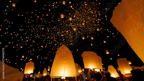 A breathtaking low-angle shot of the Yee Peng festival in Chiang Mai, showing hundreds of illuminated sky lanterns (Khom Loi) ascending into the dark night sky.
