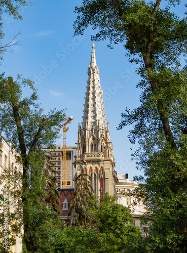 The historic building of the Church of St. Nicholas, surrounded by greenery, amidst a cityscape with modern buildings nearby during a clear day. Kyiv, Ukraine 02.08.2020
