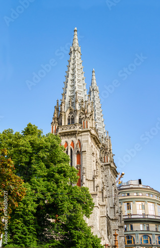The historic building of the Church of St. Nicholas, surrounded by greenery, amidst a cityscape with modern buildings nearby during a clear day. Kyiv, Ukraine 02.08.2020