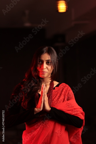 Portrait of an Indian Nepali woman in red traditional saree and black blouse under warm indoor lighting