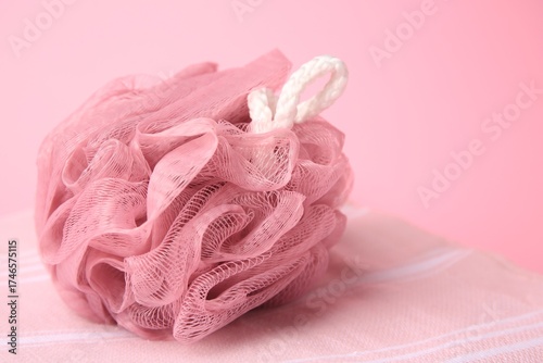 Shower puff with towel on pink background, closeup. Space for text