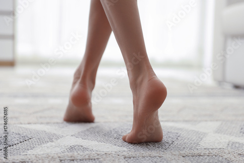 Tableau sur toile Woman walking barefoot on soft carpet with pattern at home, closeup