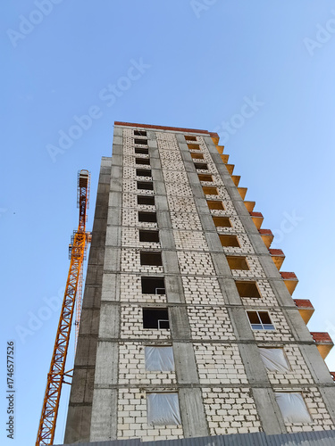 Happening high rise construction with tower crane under clear blue sky