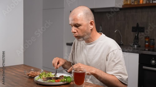 Balanced mediterranean dinner for health. Middle-aged bald man eating at home kitchen.