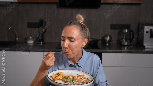 Woman eating quickly and drinking water at home. Very hungry, devouring food.