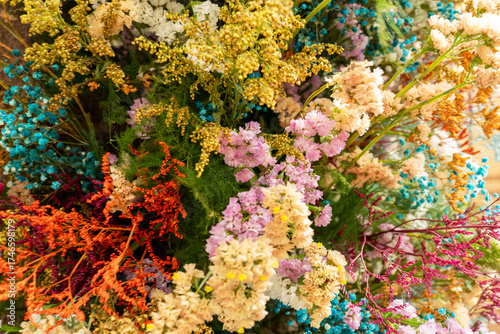 Colorful dried flower bouquet with soft pink, yellow, blue, and red hues creating a delicate, rustic charm. Close-up of decorative dried blossoms and foliage, soft focus etails and natural colors.