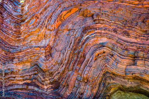 Vividly coloured and contorted rock strata in ancient layered gorge walls
