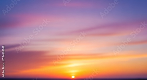 A captivating and blurred abstract background showcasing a vibrant sunset or sunrise sky. The scene features a beautiful color gradient, seamlessly transitioning from rich purples and soft pinks at th