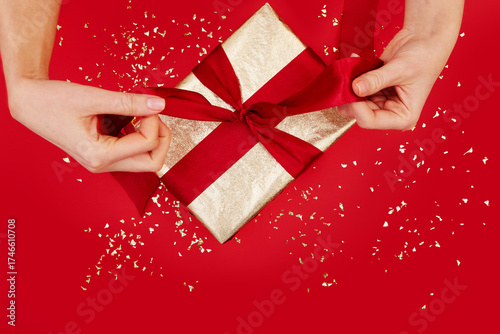 Elegantly wrapped gift box adorned with a shiny red ribbon, making it perfect for any joyful celebration event