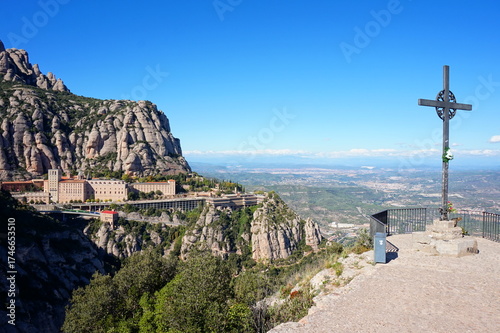 Panoramic landscape of Montserrat Monastery from the Creu de Sant Miquel cross viewpoint, overlooking the vast Catalan countryside in Spain.