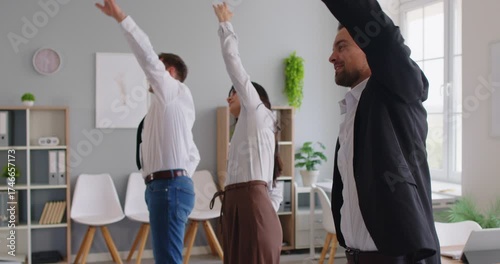 Coworkers in an office raise arms overhead, stretching during a quick exercise break. Warmup supports fitness and posture while improving mood. Quick team stretch routine for office energy.