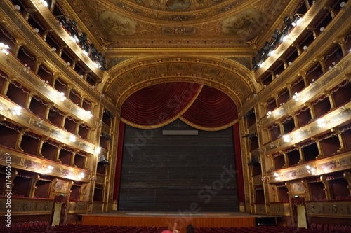 The grand auditorium and stage of the historic Teatro Massimo opera house in Palermo, Sicily, showing the ornate golden boxes and red velvet curtain