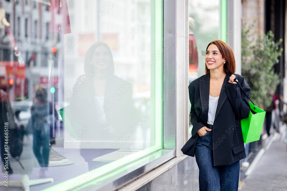 Fototapeta premium Woman holding shopping bag walking past store window