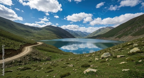 Serene lake nestled between green mountains, under a bright, cloud-filled sky