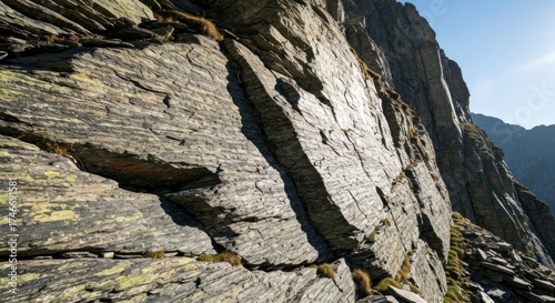 Striated mountain rockface, texture, with sunlight and small patches of vegetation