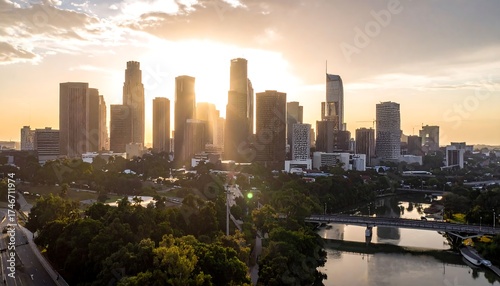 Aerial view of a city skyline at sunset. High-rise buildings and trees with the setting sun creating a golden, warm effect