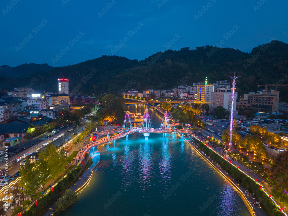 Fototapeta premium A river flows through a town decorated with lights at night in Xuan'en County, Hubei Province, China.