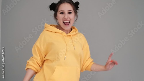 Pretty girl in a yellow sweater having fun on the bed - jumping and dancing. brunette