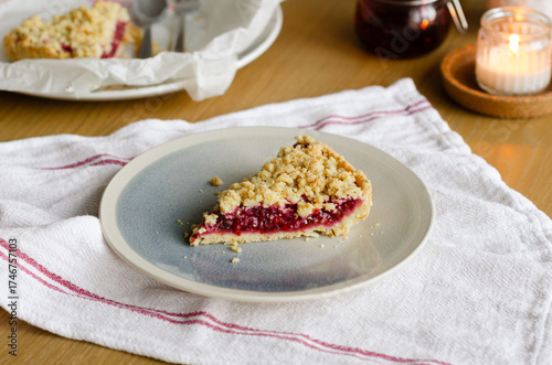 Obraz na plátne Close up of Italian sbriciolata crumble pie slice with organic plum jam on plate over white towel