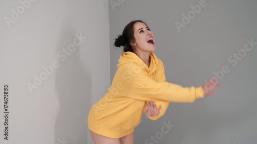 Pretty girl in a yellow sweater having fun on the bed - jumping and dancing. brunette